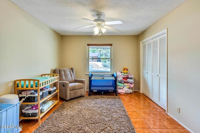 recreation room featuring tile patterned flooring, baseboards, a textured ceiling, and a ceiling fan