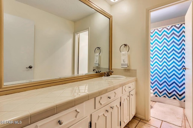 bathroom with curtained shower, tile patterned floors, toilet, and vanity