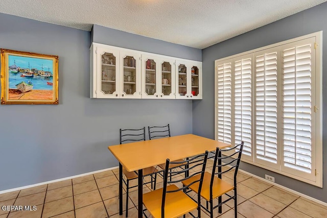 tiled dining room with a textured ceiling and baseboards