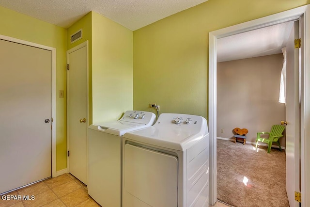 washroom with visible vents, light carpet, washer and clothes dryer, a textured ceiling, and laundry area