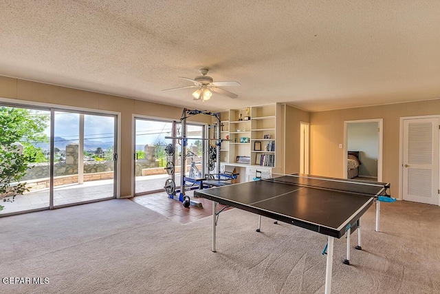 playroom with a ceiling fan, carpet floors, and a textured ceiling