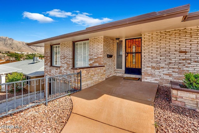 doorway to property with brick siding, central AC unit, and a mountain view