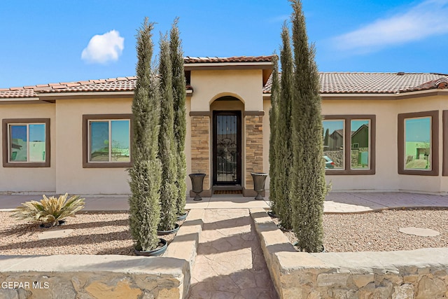 view of front of home featuring stucco siding, stone siding, and a tiled roof