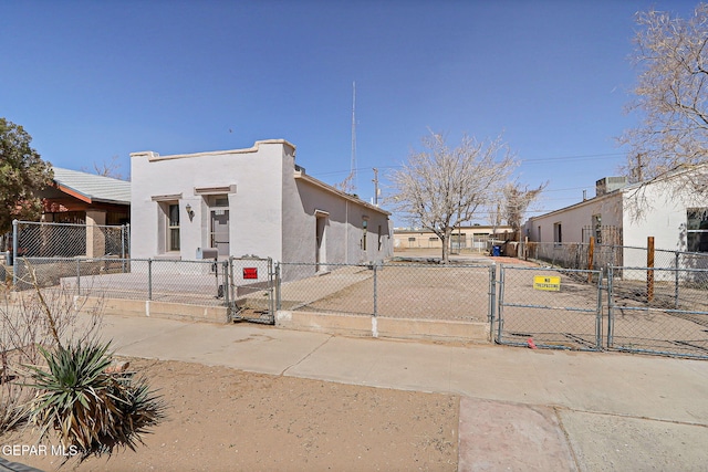 view of front facade with a fenced front yard, a gate, and stucco siding