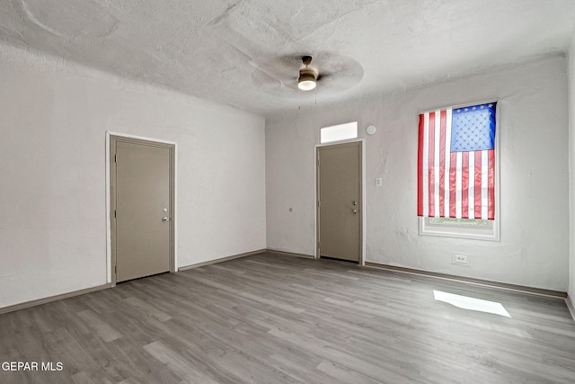 empty room featuring a textured ceiling, wood finished floors, and a ceiling fan