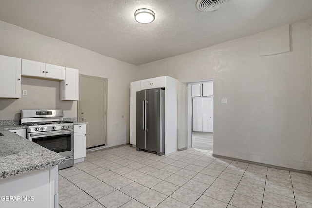 kitchen featuring light stone counters, appliances with stainless steel finishes, visible vents, and white cabinetry