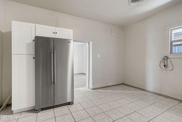 kitchen featuring light tile patterned floors, visible vents, high quality fridge, and white cabinetry