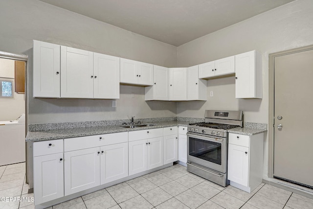 kitchen with gas stove, white cabinetry, a sink, light stone countertops, and washer / dryer