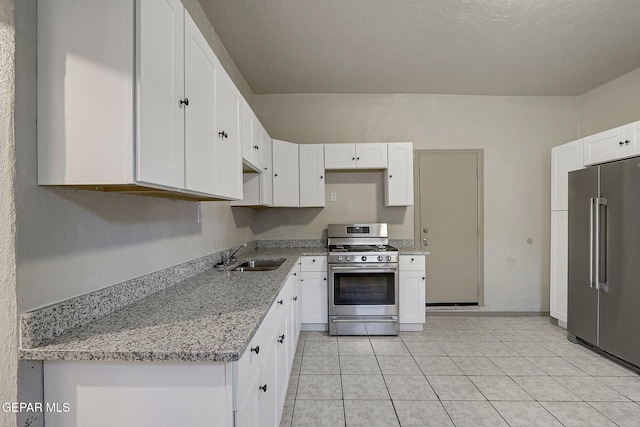 kitchen with white cabinets, appliances with stainless steel finishes, light stone countertops, a sink, and light tile patterned flooring