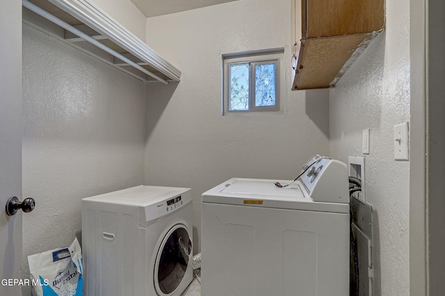 laundry room with cabinet space, separate washer and dryer, and a textured wall