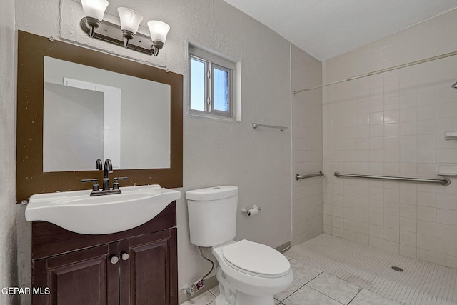 bathroom featuring toilet, tile patterned flooring, tiled shower, and vanity