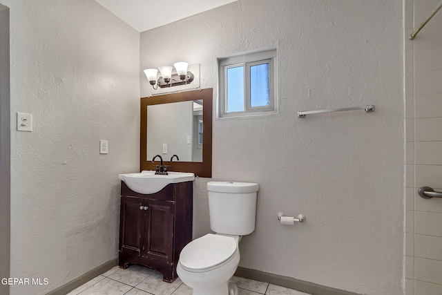 bathroom featuring toilet, a textured wall, baseboards, and vanity