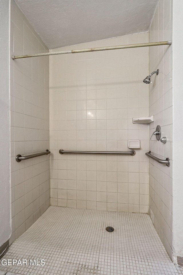 full bath featuring tiled shower and a textured ceiling