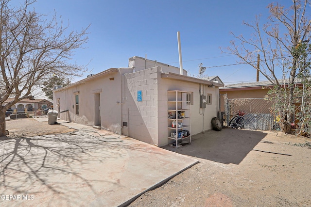 rear view of property with concrete block siding, a patio area, and fence