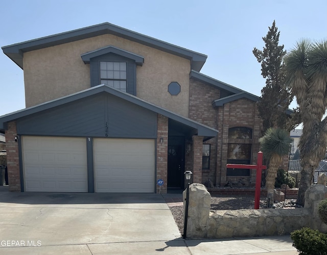 view of front of house featuring driveway, stucco siding, a garage, and brick siding