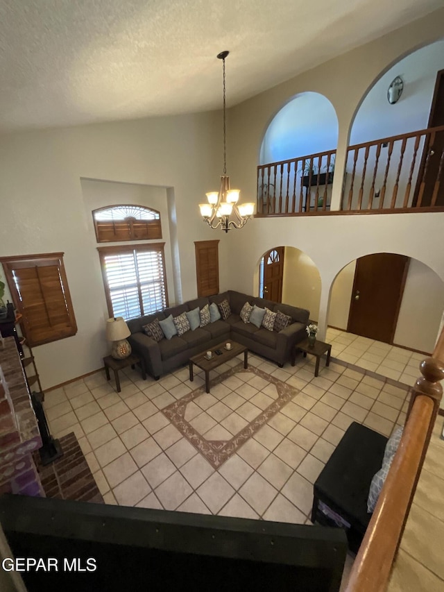 tiled living room featuring a chandelier, a high ceiling, a textured ceiling, and arched walkways