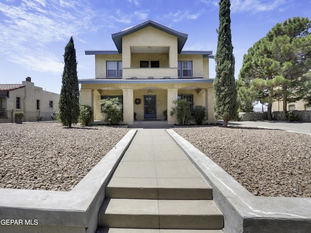 view of front facade featuring fence, a porch, and stucco siding