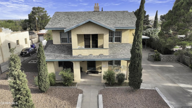 view of front facade featuring covered porch, a shingled roof, and stucco siding