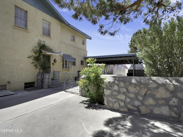 view of side of property with fence, a gate, and stucco siding