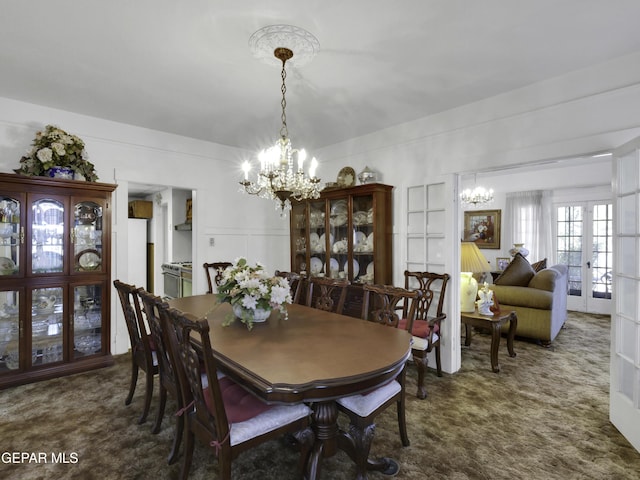 carpeted dining space with a decorative wall, a notable chandelier, and french doors