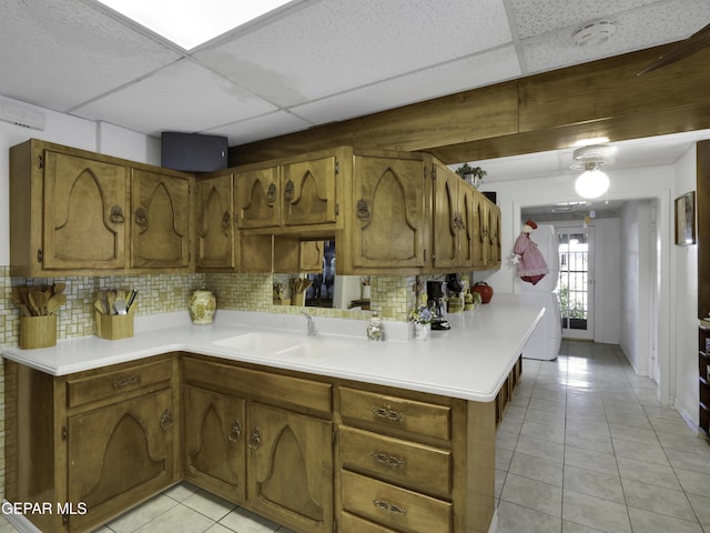 kitchen with brown cabinetry, tasteful backsplash, light countertops, and a sink