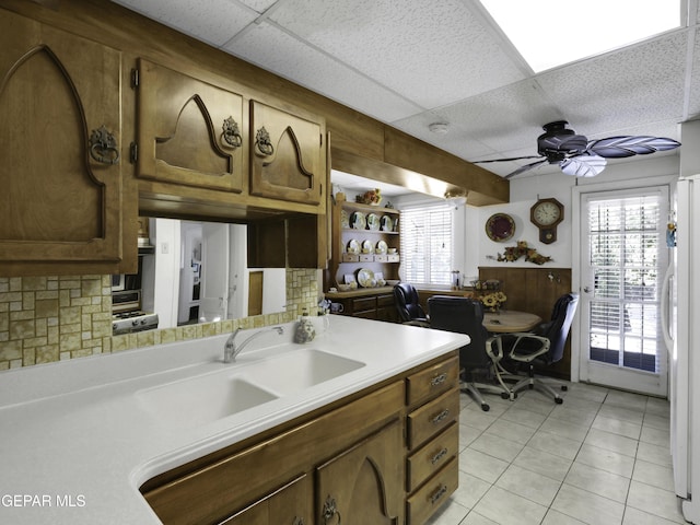 kitchen featuring ceiling fan, light tile patterned flooring, light countertops, backsplash, and freestanding refrigerator