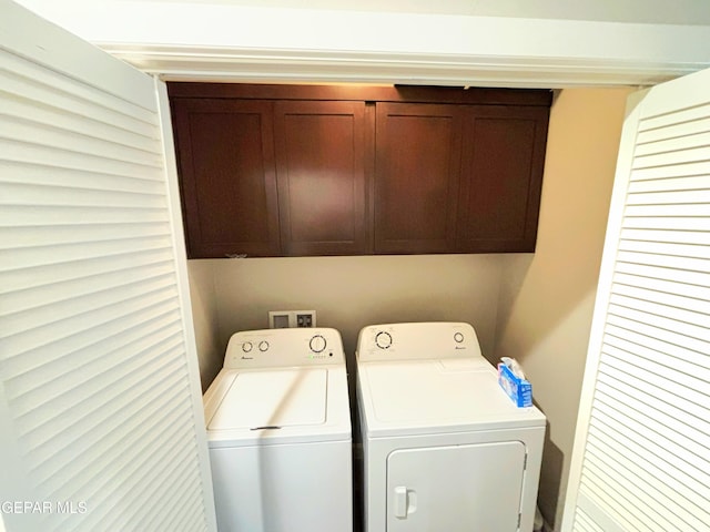 clothes washing area featuring cabinet space and washer and clothes dryer