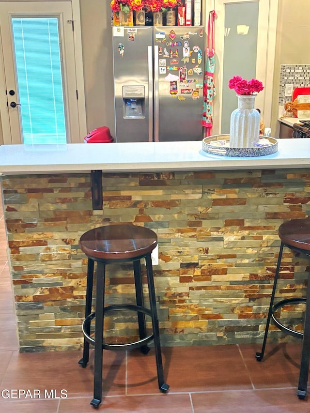 bar featuring stainless steel refrigerator with ice dispenser and a bar