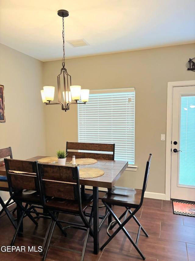 dining room with baseboards, dark wood finished floors, visible vents, and an inviting chandelier