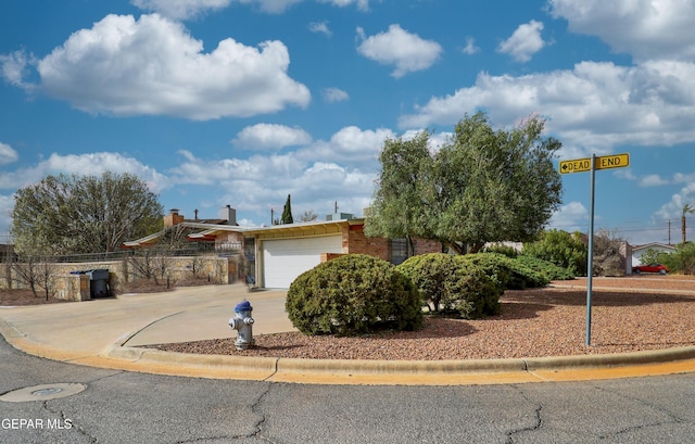 view of front of house featuring an attached garage, fence, concrete driveway, and brick siding