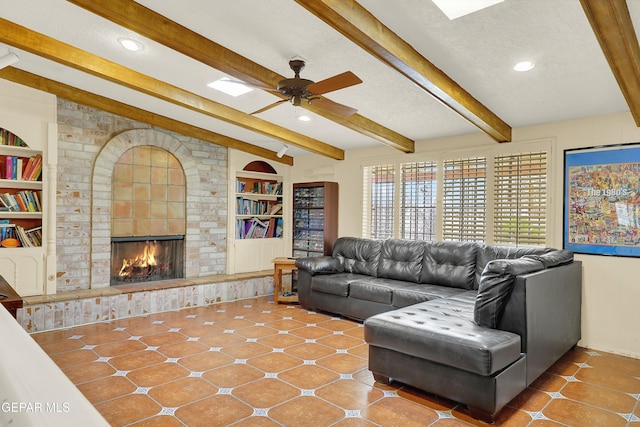 tiled living room featuring built in features, a fireplace, a ceiling fan, a textured ceiling, and beamed ceiling