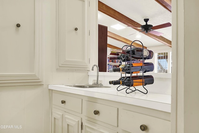 interior space featuring a ceiling fan, vanity, beam ceiling, and a decorative wall