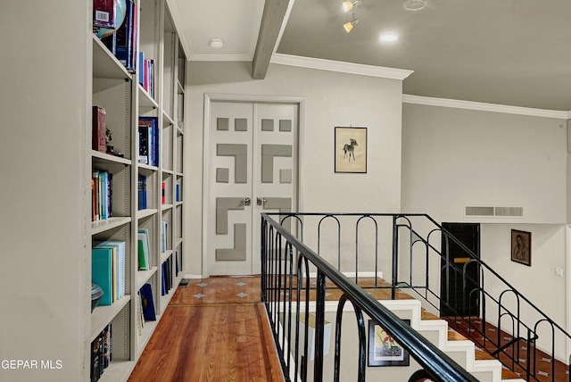 corridor featuring visible vents, beamed ceiling, wood finished floors, and ornamental molding