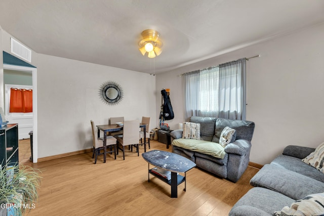 living area with a ceiling fan, light wood-type flooring, visible vents, and baseboards