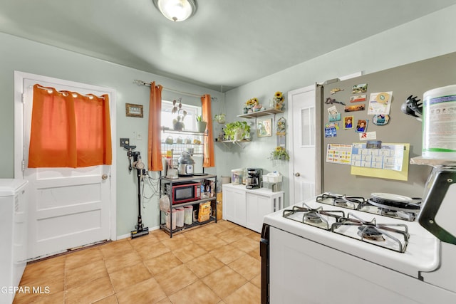 kitchen with light tile patterned flooring, white range with gas cooktop, light countertops, freestanding refrigerator, and open shelves