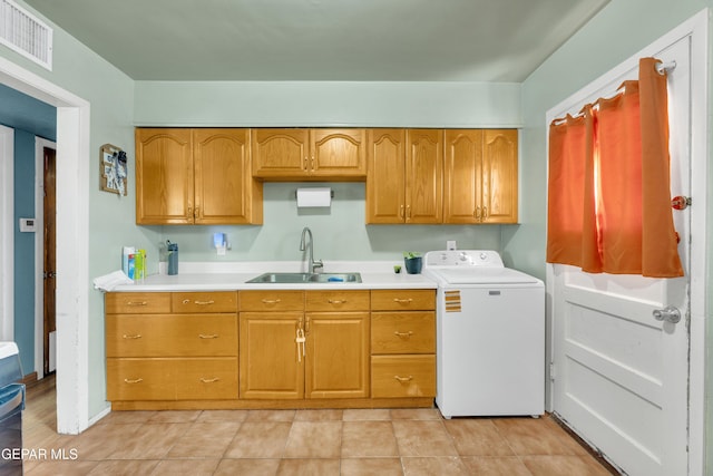 kitchen featuring brown cabinets, washer / clothes dryer, light countertops, visible vents, and a sink