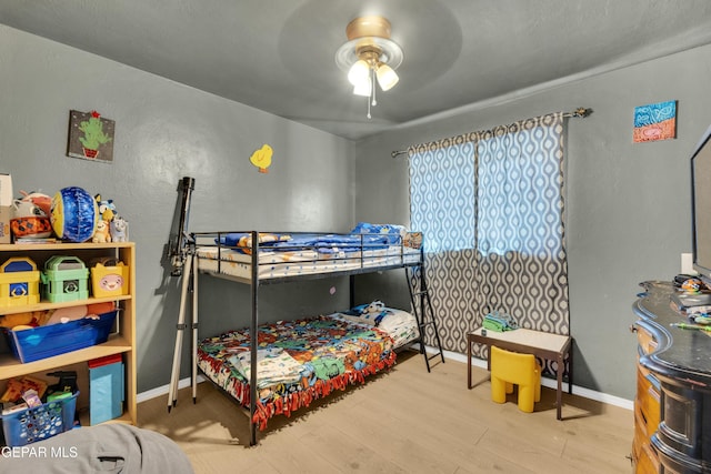 bedroom featuring a ceiling fan, baseboards, and wood finished floors