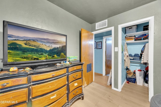 bedroom with light wood-style floors, a closet, and visible vents