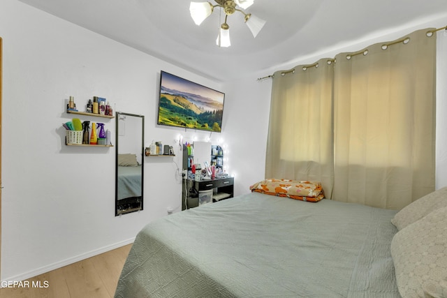 bedroom with ceiling fan, baseboards, and wood finished floors