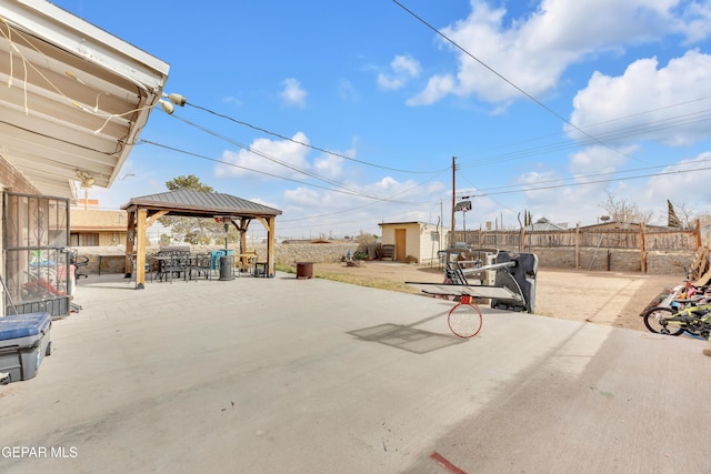 view of patio featuring fence, an outdoor structure, and a gazebo