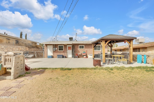 rear view of house with a patio, cooling unit, brick siding, fence, and a gazebo