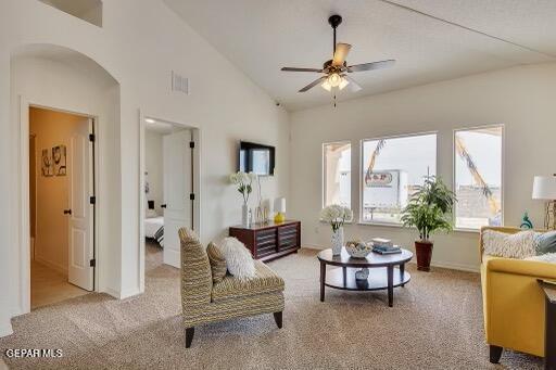 living area with lofted ceiling, visible vents, arched walkways, and light colored carpet