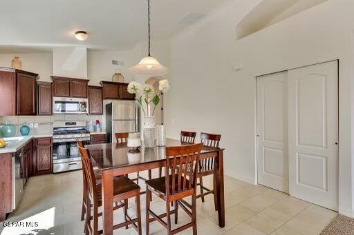 dining room featuring light tile patterned flooring and vaulted ceiling