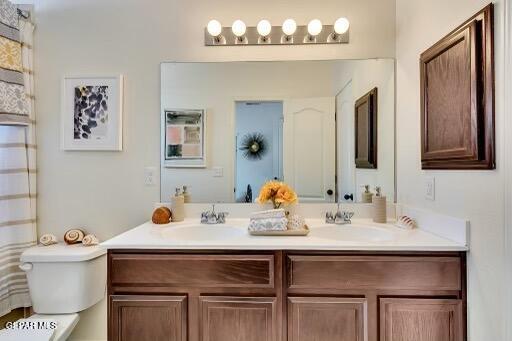 full bath featuring double vanity, a sink, and toilet