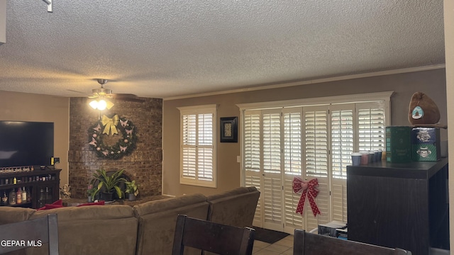 living area featuring tile patterned floors, a textured ceiling, ceiling fan, and ornamental molding