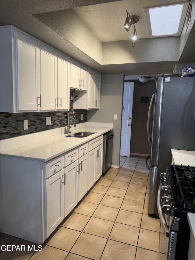 kitchen featuring a sink, stainless steel appliances, light tile patterned floors, and white cabinetry