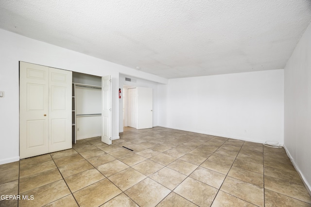 unfurnished bedroom with a closet, a textured ceiling, and light tile patterned floors