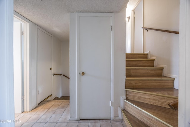 stairs with a textured ceiling and tile patterned flooring