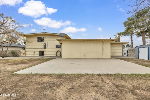 rear view of house with a patio area, an outdoor structure, and a storage unit