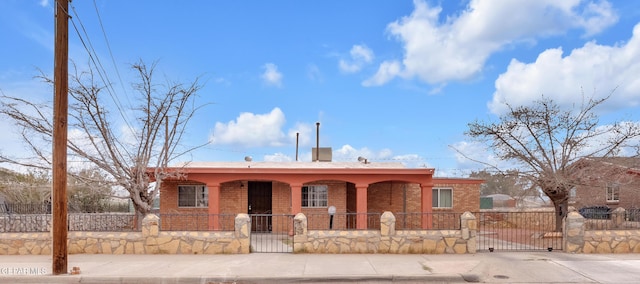 ranch-style home featuring covered porch, brick siding, a fenced front yard, and a gate